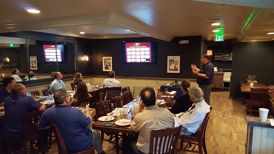 A man is giving a presentation at a restaurant for a company event, with Millersville and Baltimore, MD