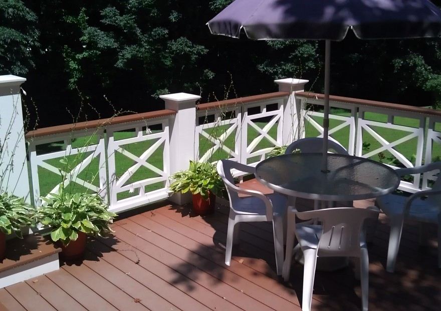 A deck in Millersville and Baltimore, MD, featuring white chairs and a large umbrella for shade