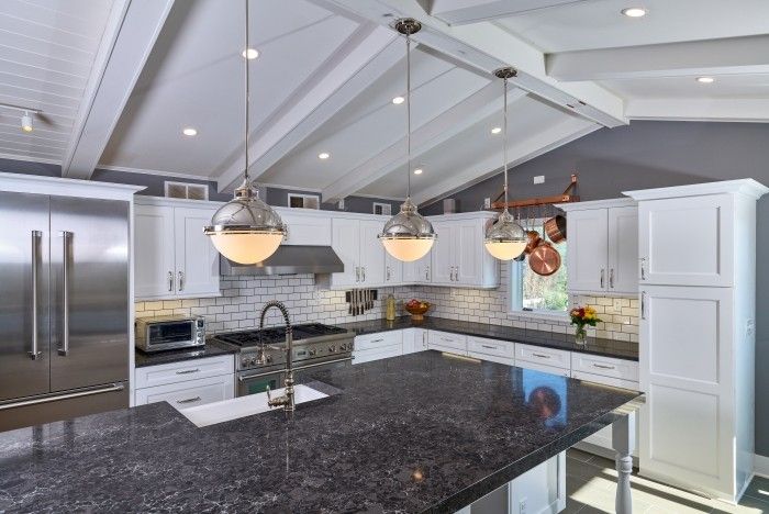 Kitchen with black quartz island, white cabinets, and pendant lighting