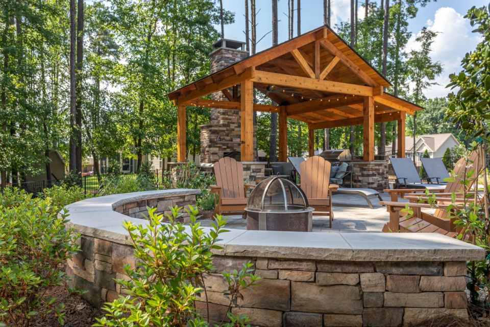 Custom-built rustic wooden pavilion featuring a natural stone fireplace and integrated seating wall
