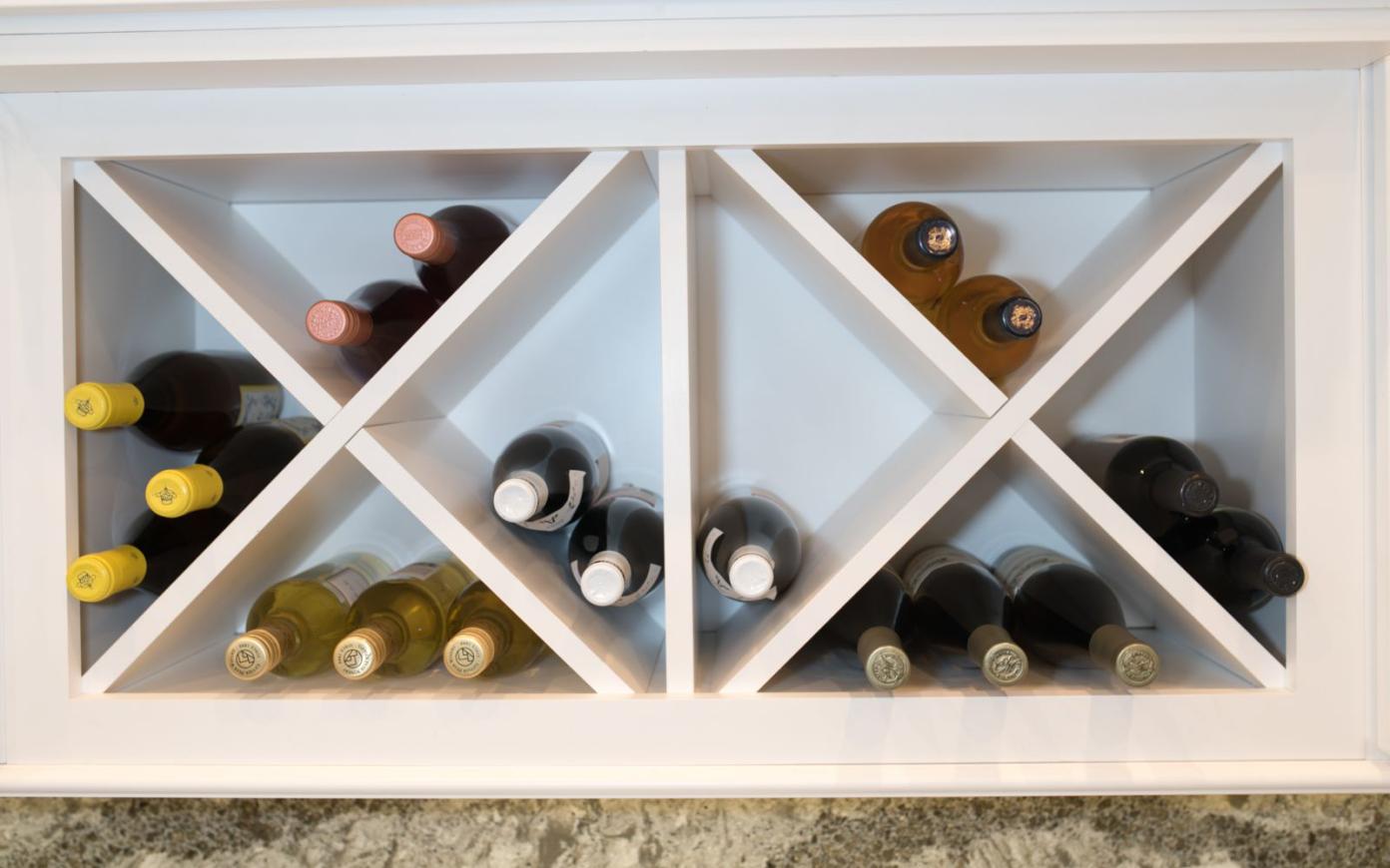 A sleek white cabinet filled with wine bottles in the modern kitchen located in Baltimore, MD