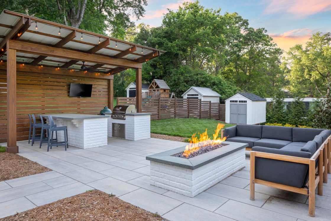 An Outdoor living space features a modern pergola and a custom-built, rectangular fire pit