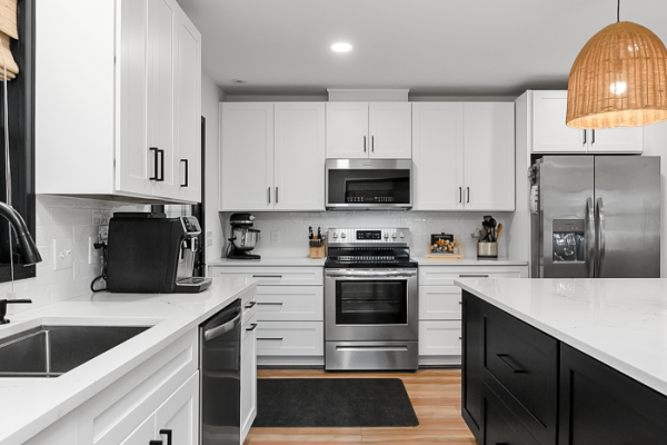 Modern white kitchen with black islands and stainless appliances in home