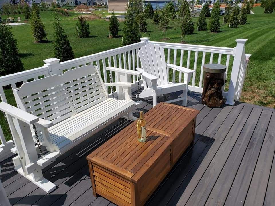 A wooden bench and two white chairs on a deck, part of Projects in Millersville and Baltimore, MD